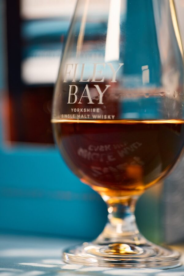 The dark Filey Bay Yorkshire Day 2024 single malt whisky shines in a glass