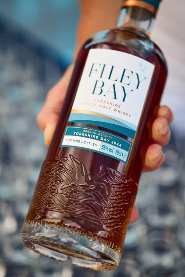 The Filey Bay Yorkshrie Day 2024 bottle lying in a hand, catching the light