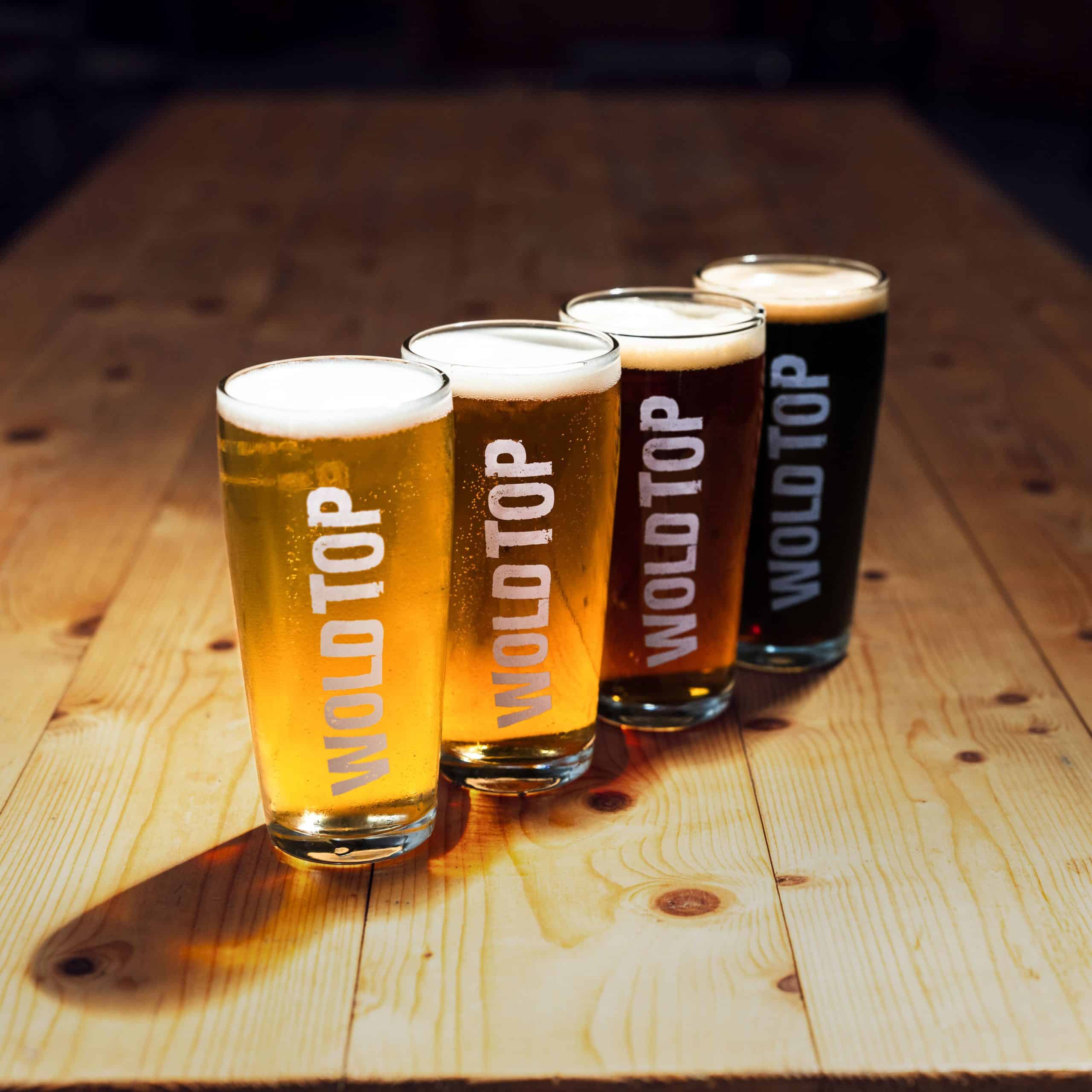A shot of 4 pint glasses of Wold Top beer showing the spectrum of colours. Lager, Pale Ale, Session bitter and Porter.